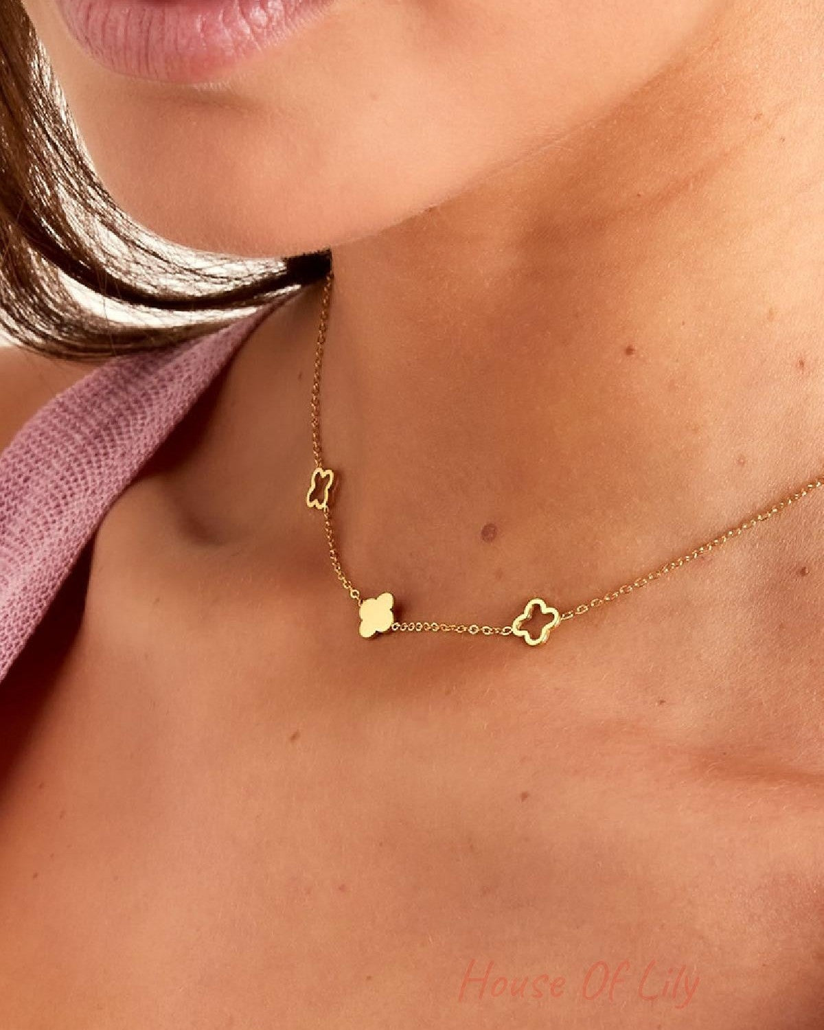Detailed view of gold-tone clover charm necklace on model showcasing the chain and charm design