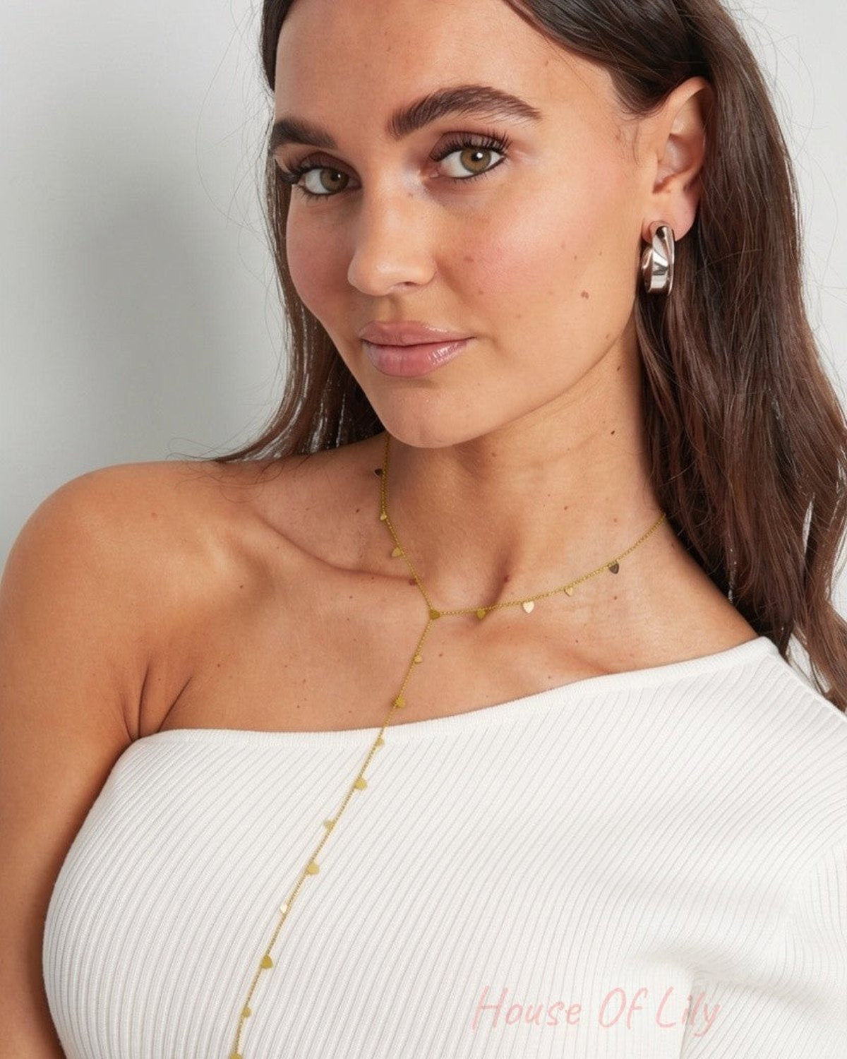 Cupids Drip: Delicate gold Y-necklace featuring small heart-shaped charms along a fine chain on a model.