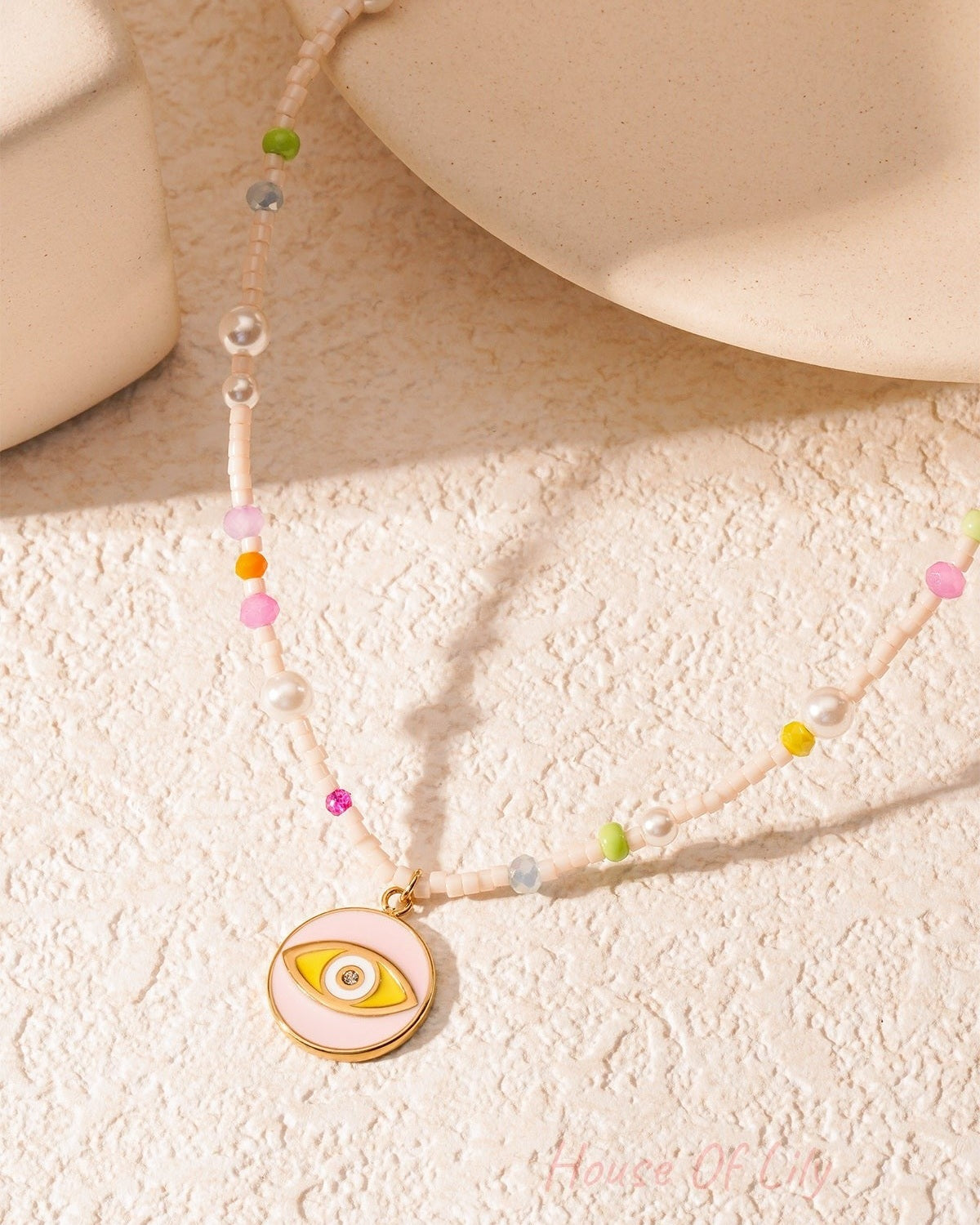 Artistic shot of pastel beaded necklace with eye charm casting shadow on textured background