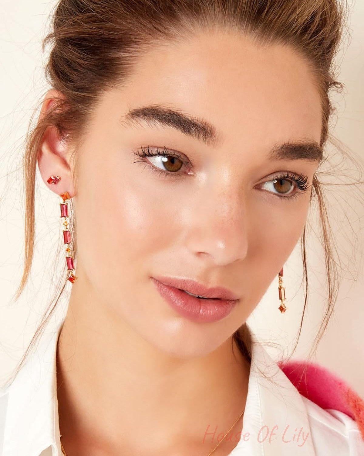 Portrait of a woman with subtle makeup wearing gold earrings with red and orange stones, styled for a youthful and aesthetic look.