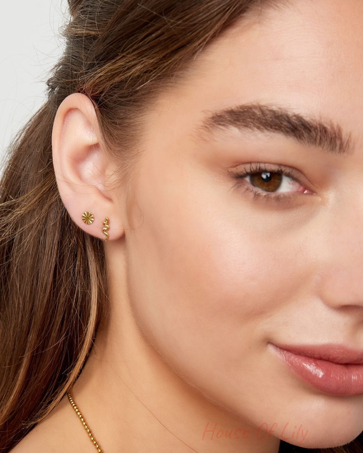Side view of woman smiling, showcasing her gold snake stud earring and delicate jewelry