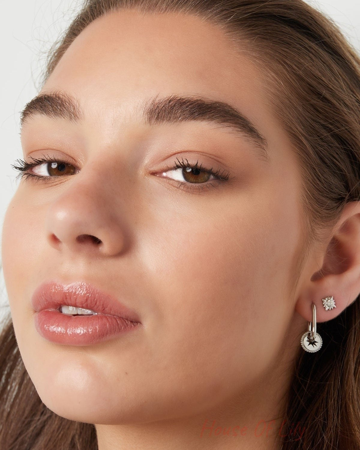 Portrait of woman wearing silver sunburst crystal stud earrings with neutral makeup and natural hair