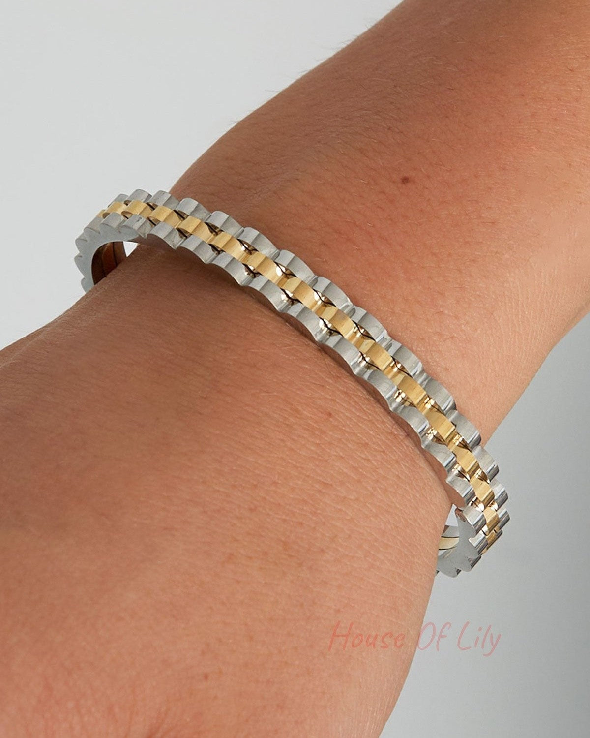 Closeup of two-tone scalloped edge bangle bracelet on model wrist showing silver and gold details