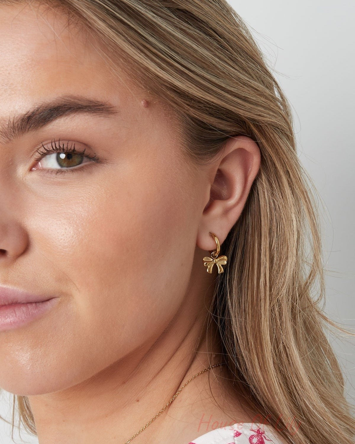 Another close-up of the woman's face showcasing the playful bow hoop earring from a slightly different angle.