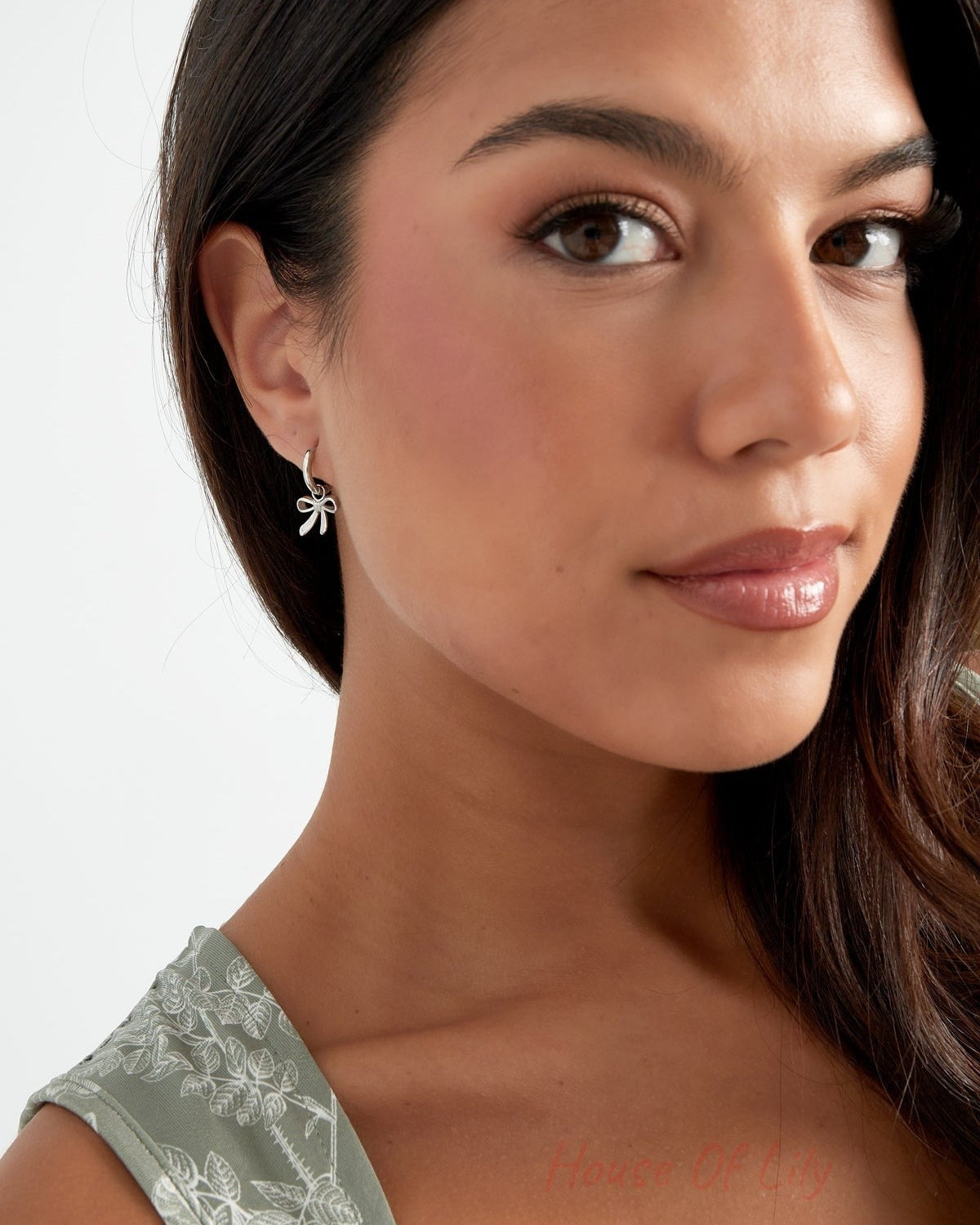 Silver bow charm hoop earrings on white background