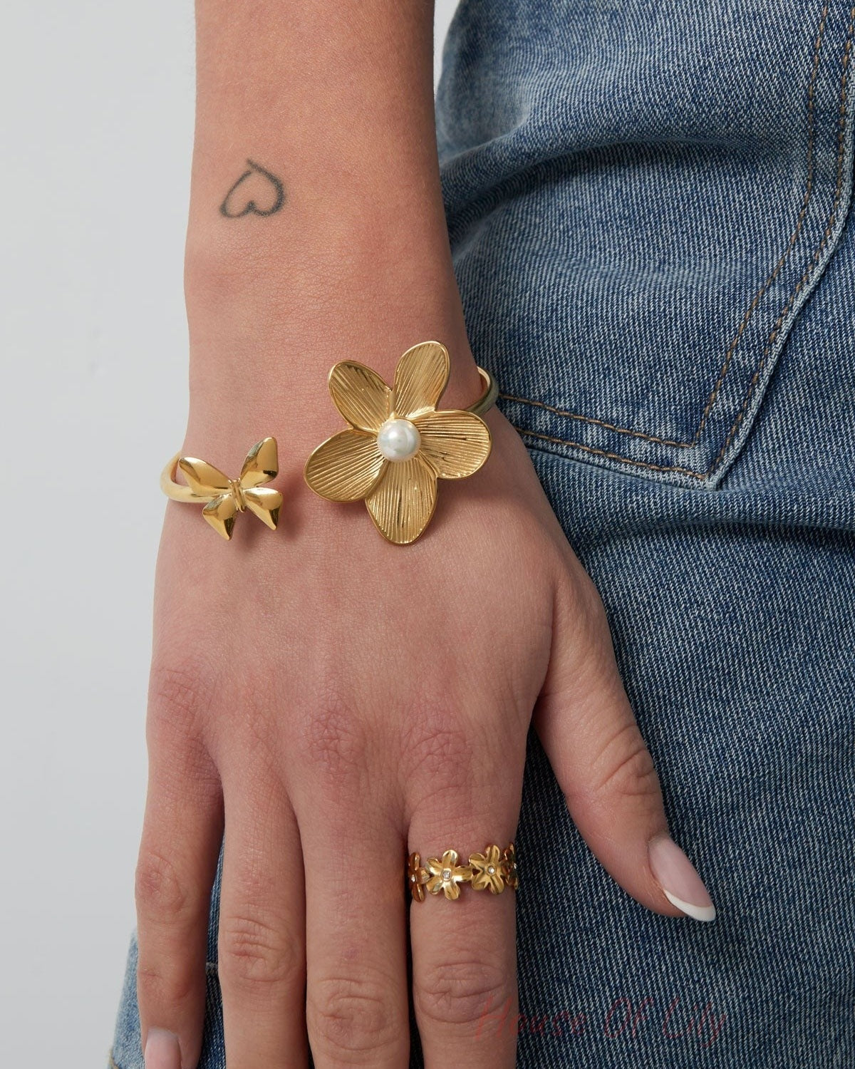 Model wearing gold butterfly flower cuff bracelet paired with gold flower ring and denim jeans