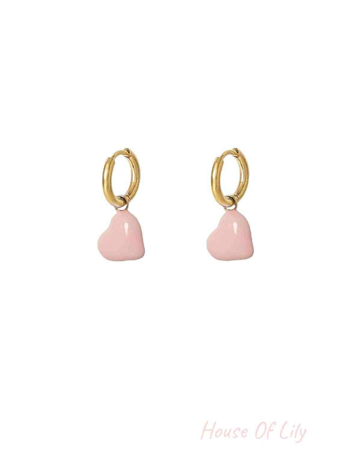 Pair of gold hoop earrings with baby pink enamel hearts displayed on white background