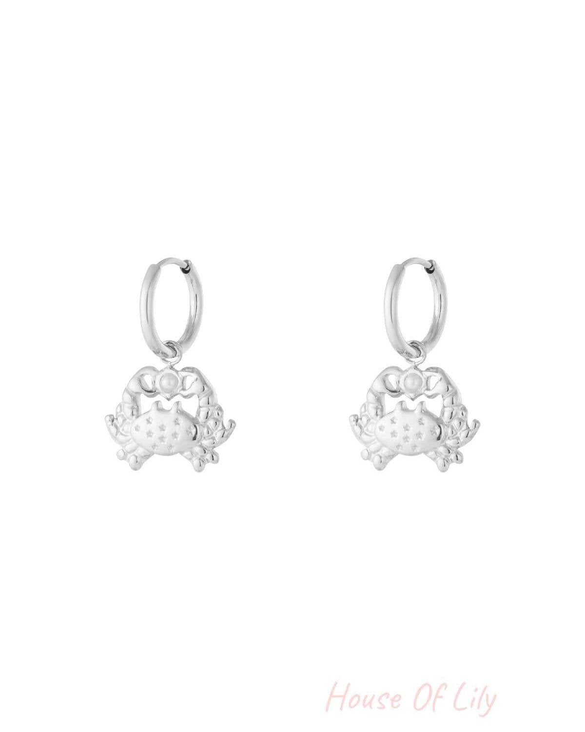 Pair of silver crab-shaped drop hoop earrings with star engravings and pearl detail.