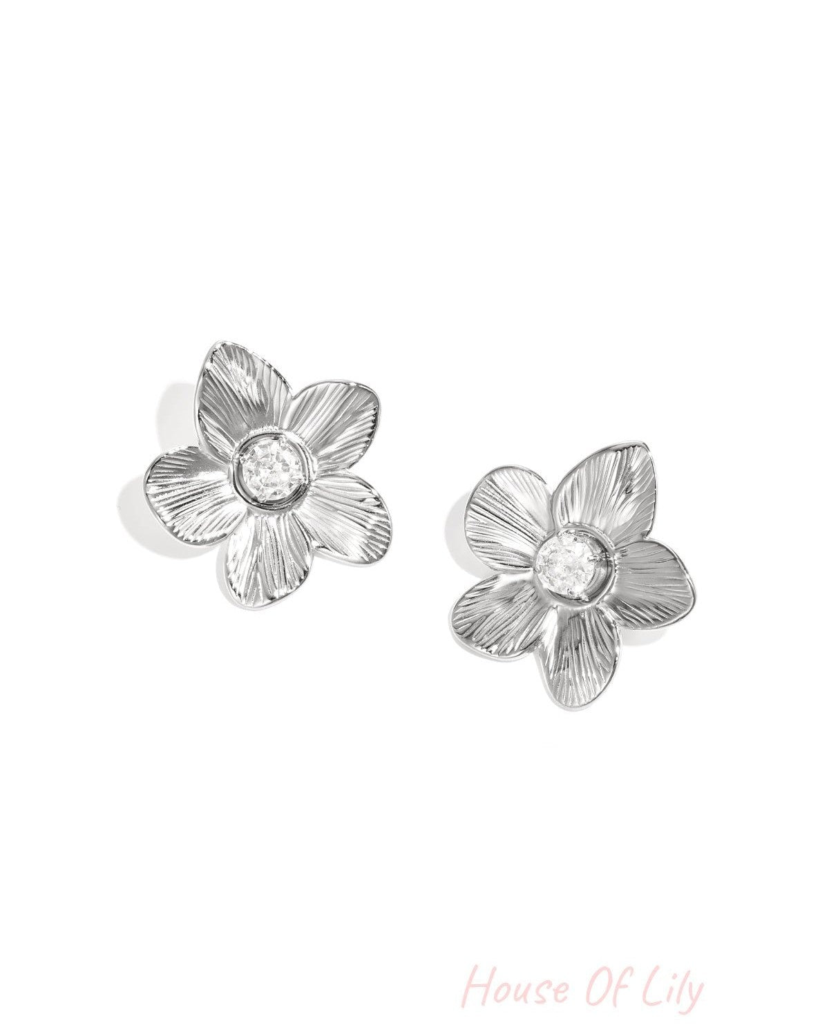 Close-up of silver floral zircon stud earrings on white background showing detailed petal textures