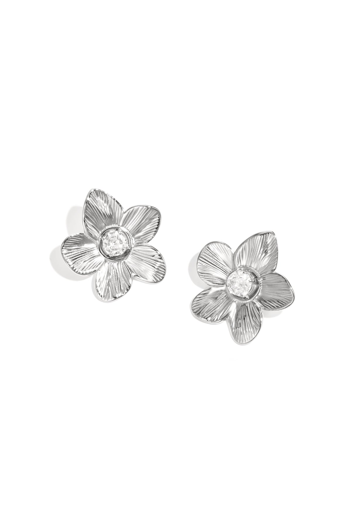 Close-up of silver floral zircon stud earrings on white background showing detailed petal textures