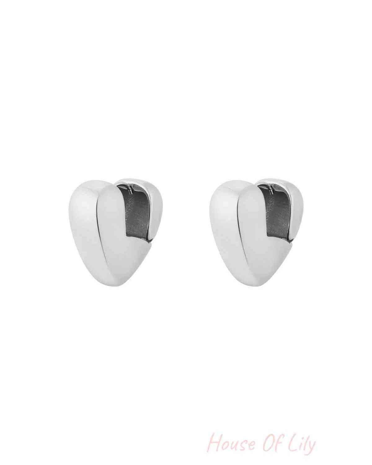Pair of chunky silver heart-shaped hoop earrings with smooth polished finish isolated on white