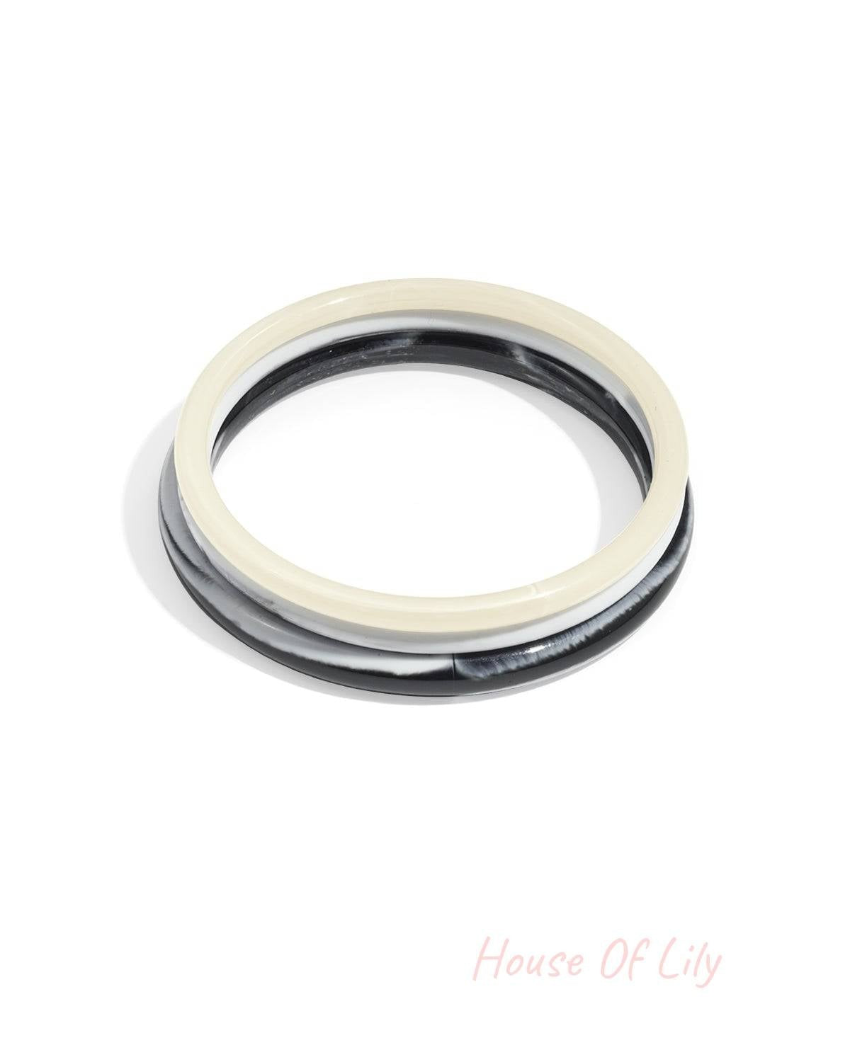 Set of two resin bangle bracelets in solid cream and marbled black and white, featuring a smooth, minimalist design.