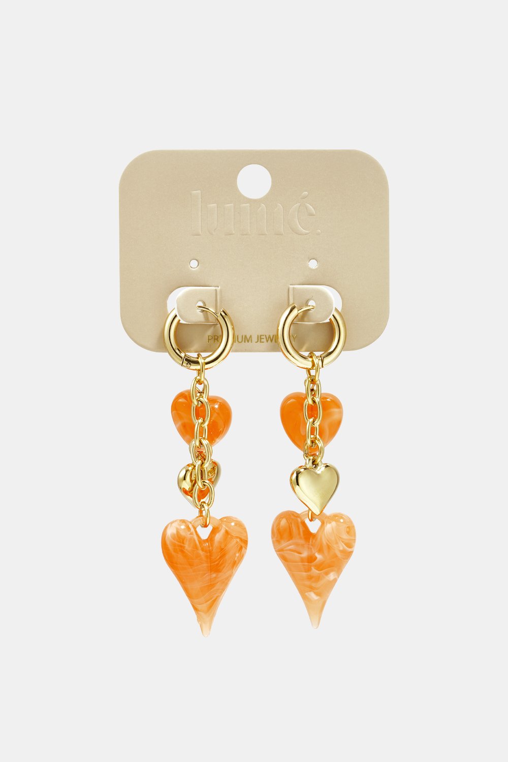 Gold dangle earrings featuring orange marbled heart charms and gold heart accents on a branded jewelry card.