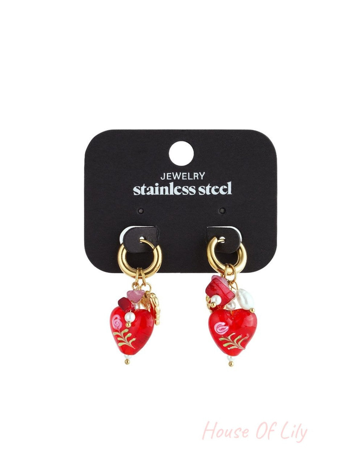 Gold hoop earrings with red heart charms featuring floral accents, small pearls, and pink beads on a display card.