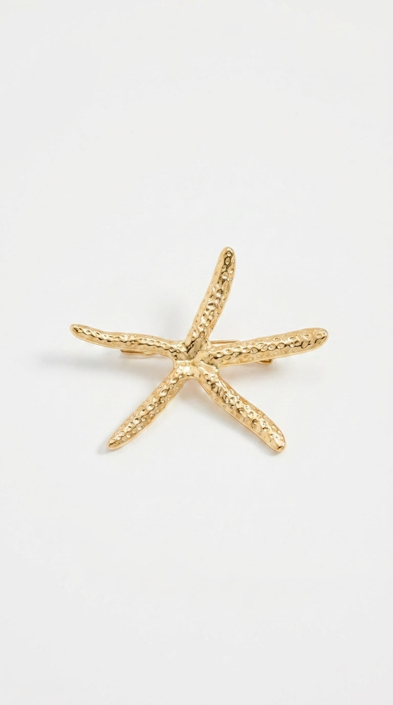 Gold-toned starfish brooch with a textured, hammered metal finish on a plain white background.