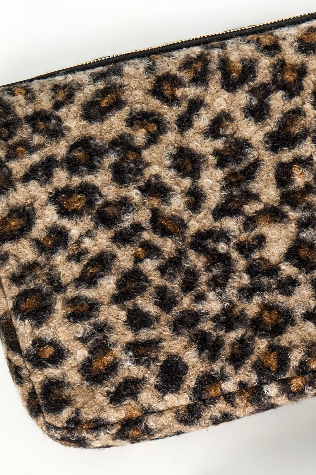 Close-up detail of textured boucle leopard print fabric in warm brown and black tones