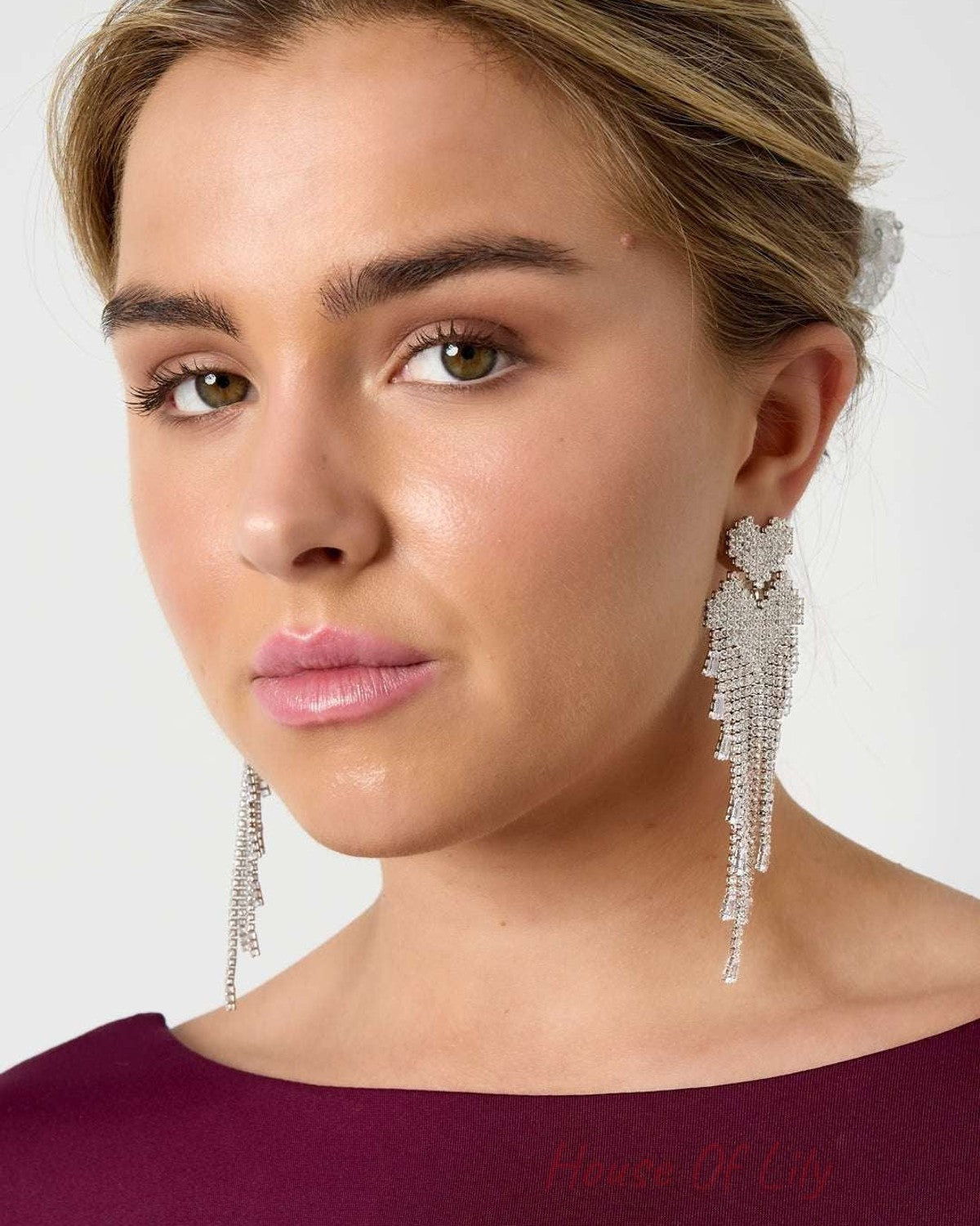 Close-up of model wearing silver-tone crystal cascade earrings styled with burgundy top and neutral makeup