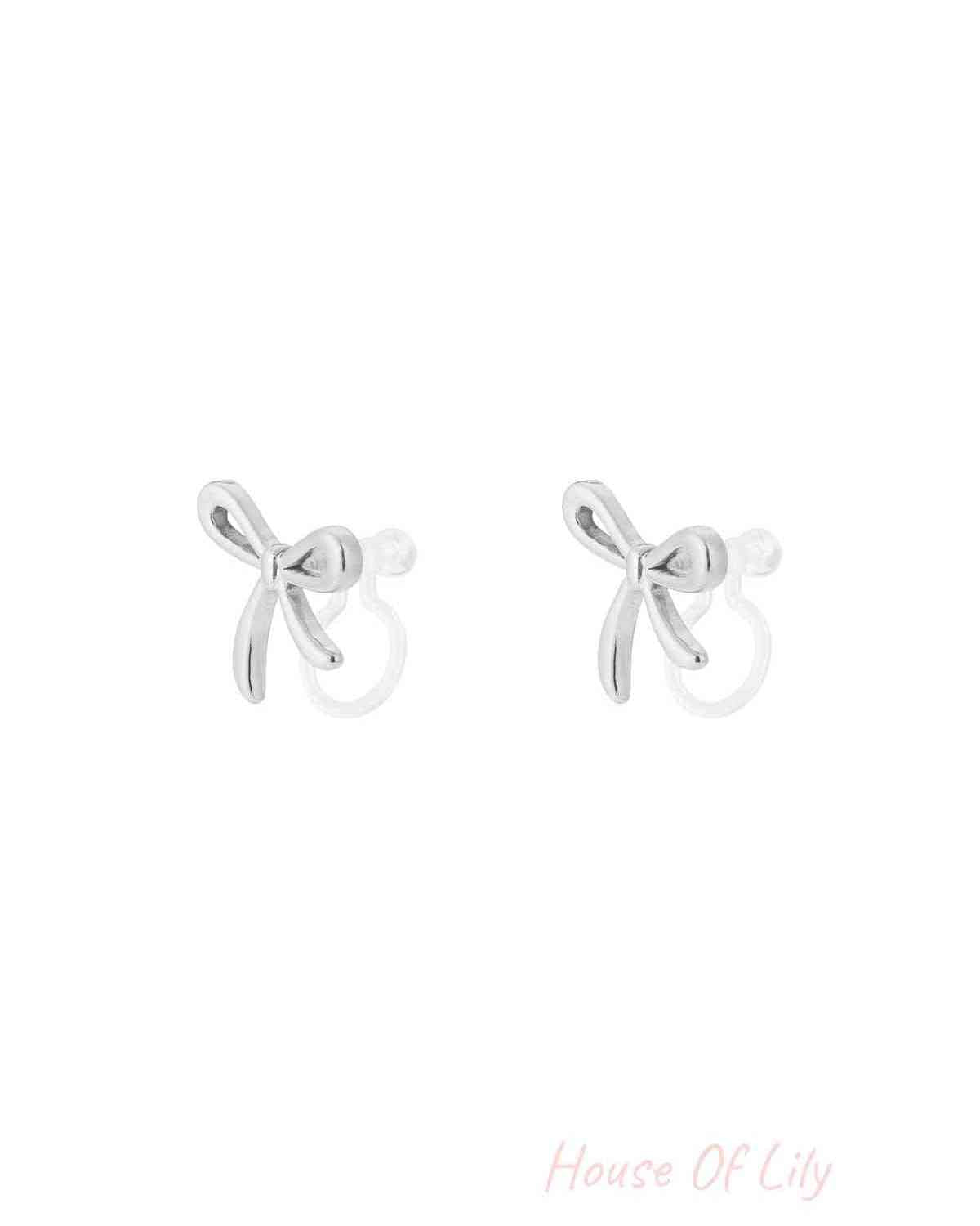 Pair of silver bow-shaped clip-on earrings with smooth polished finish on white background