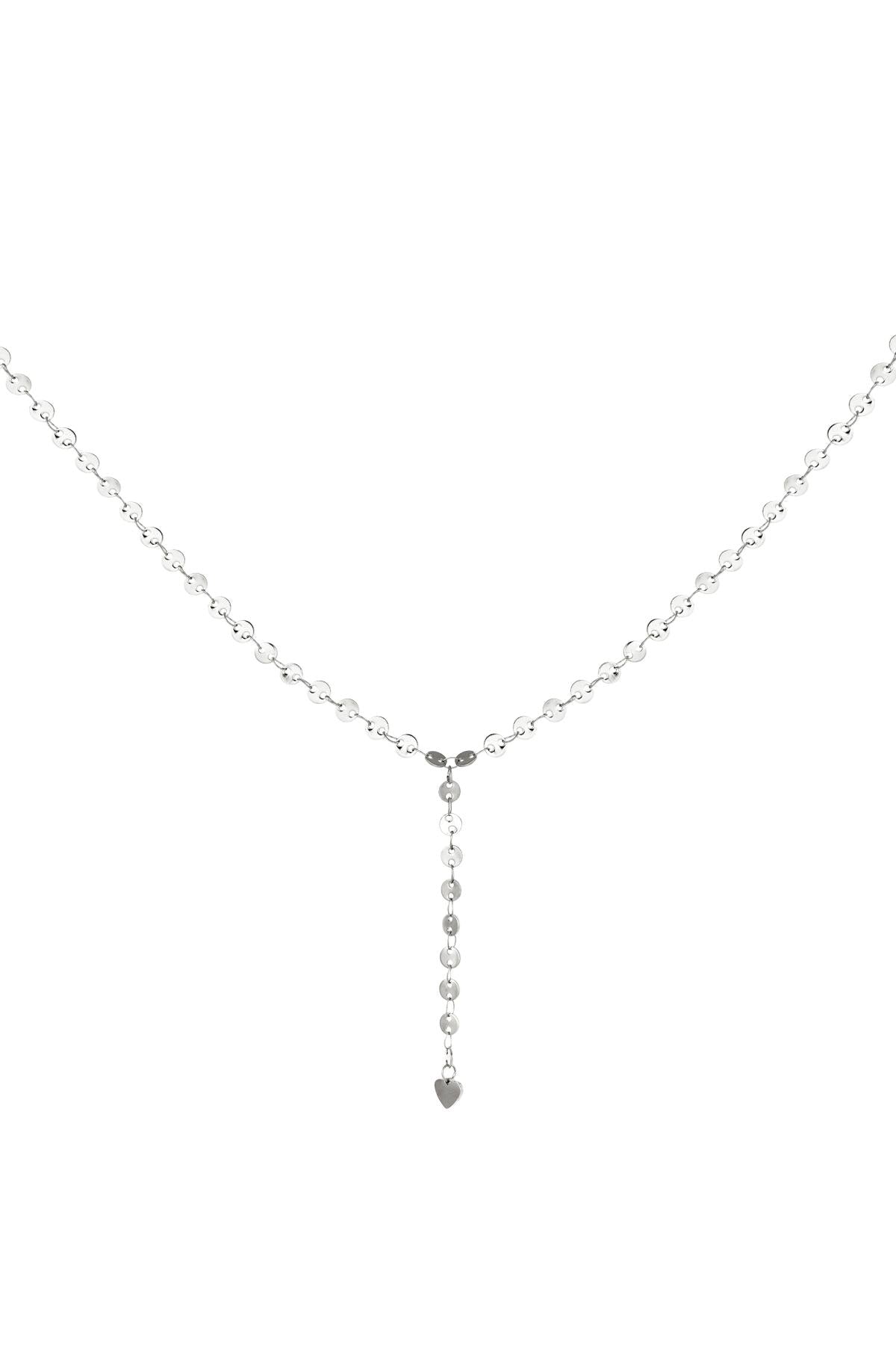 Close-up view of the silver version of the Y-chain necklace with circular discs and a small heart charm at the end