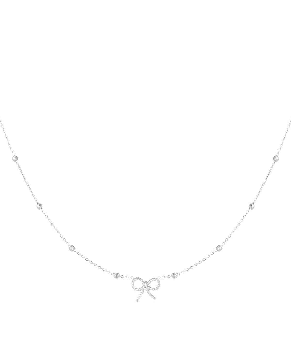 Detailed shot of a delicate silver bow pendant necklace with a fine chain and spaced bead accents