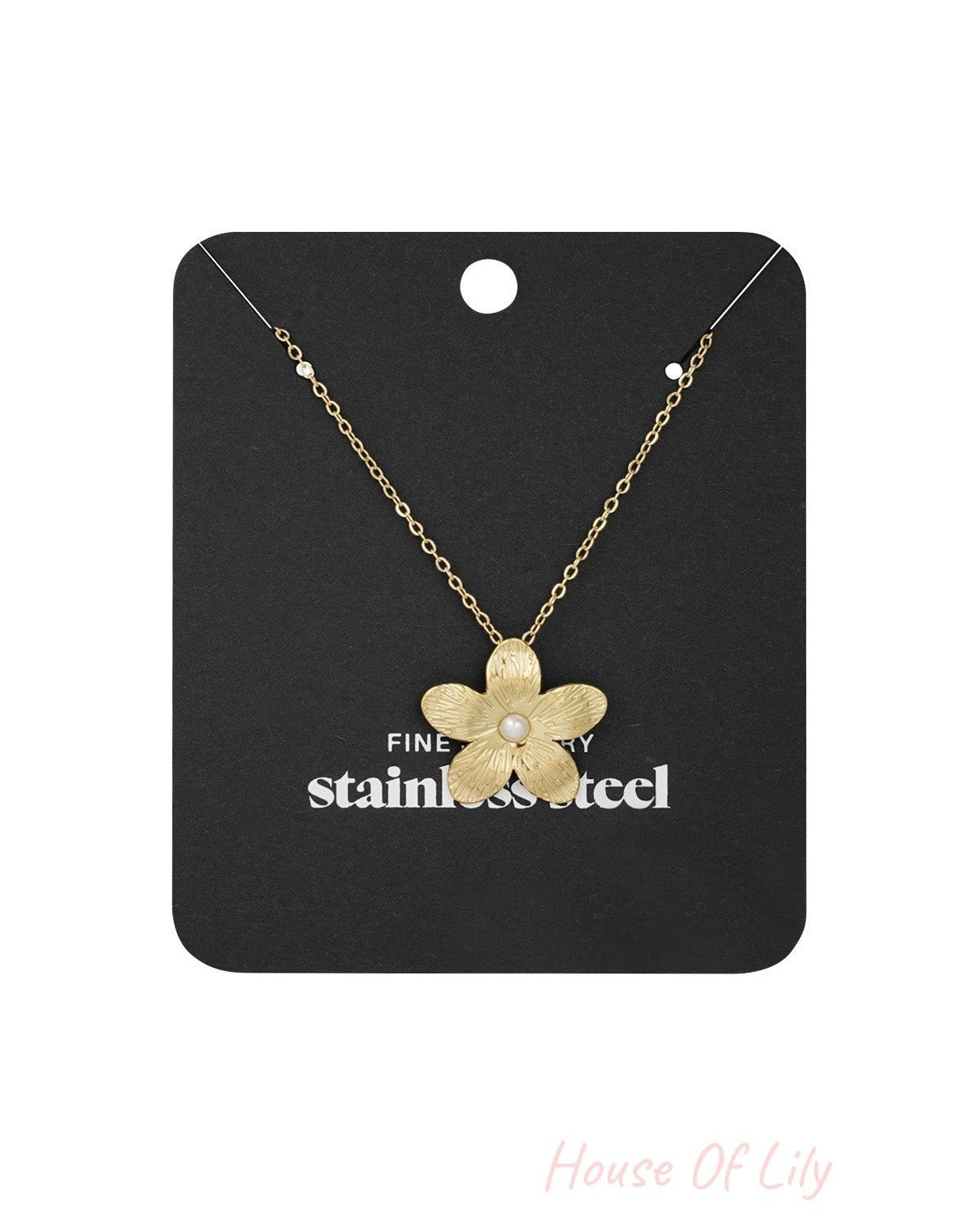 Gold flower pendant necklace displayed on a black card labelled 'stainless steel fine jewelry'