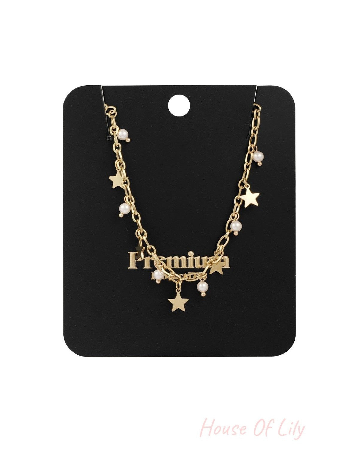 Gold-tone star and pearl charm necklace displayed on a black retail card backing