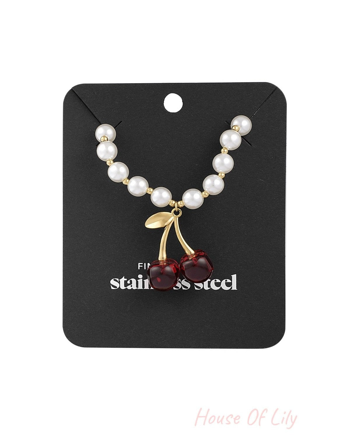 Pearl and cherry pendant necklace displayed on black branded card packaging