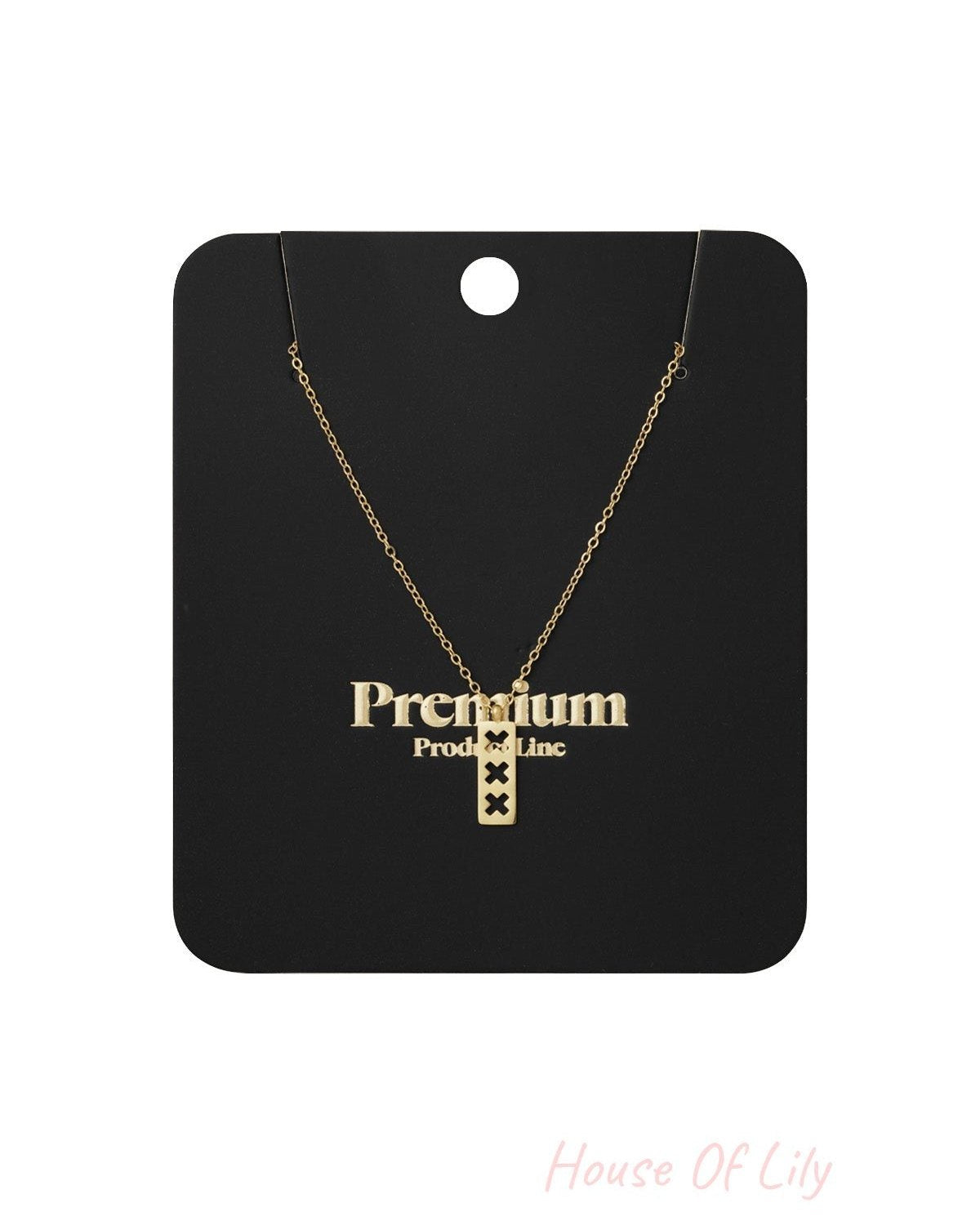 Gold triple X pendant necklace displayed on black Premium Product Line card packaging with chain arranged neatly.