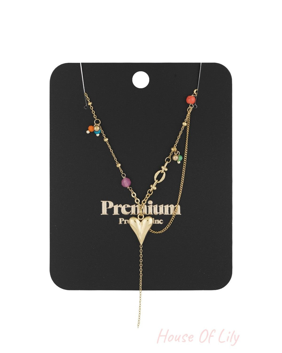 Gold heart pendant necklace displayed on black card with colourful bead accents and hanging chain detail