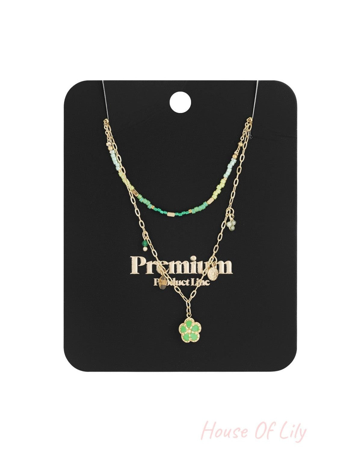Packaged double-layered necklace displayed against a black card with gold text, showing green beads and flower pendant