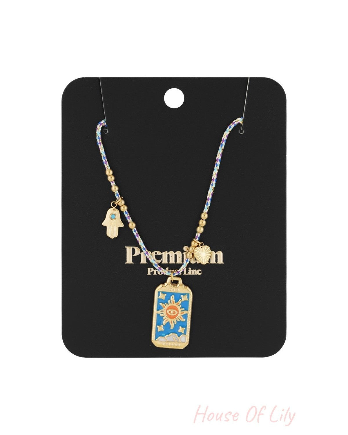 Packaged braided necklace with gold sun, heart, and Hamsa hand charms on black product card