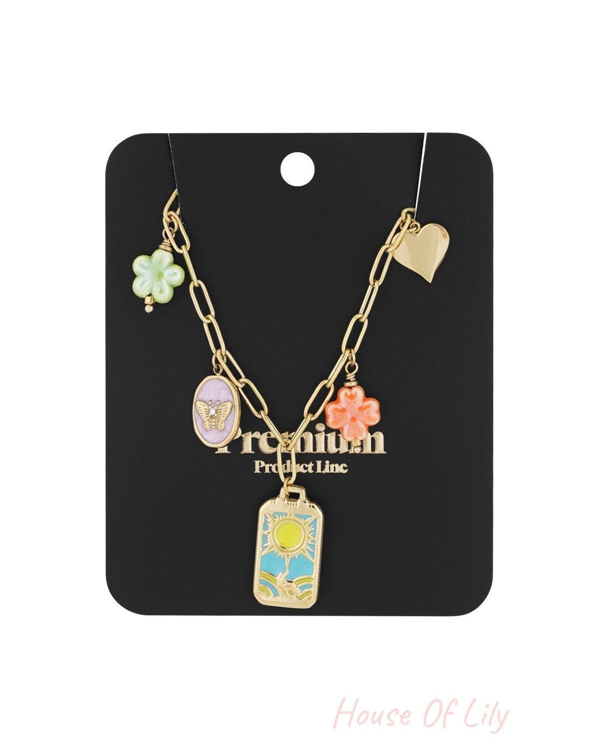 Packaged gold-tone charm link necklace displayed on black card featuring butterfly cameo, sun charm, flower charms, and turquoise heart charm