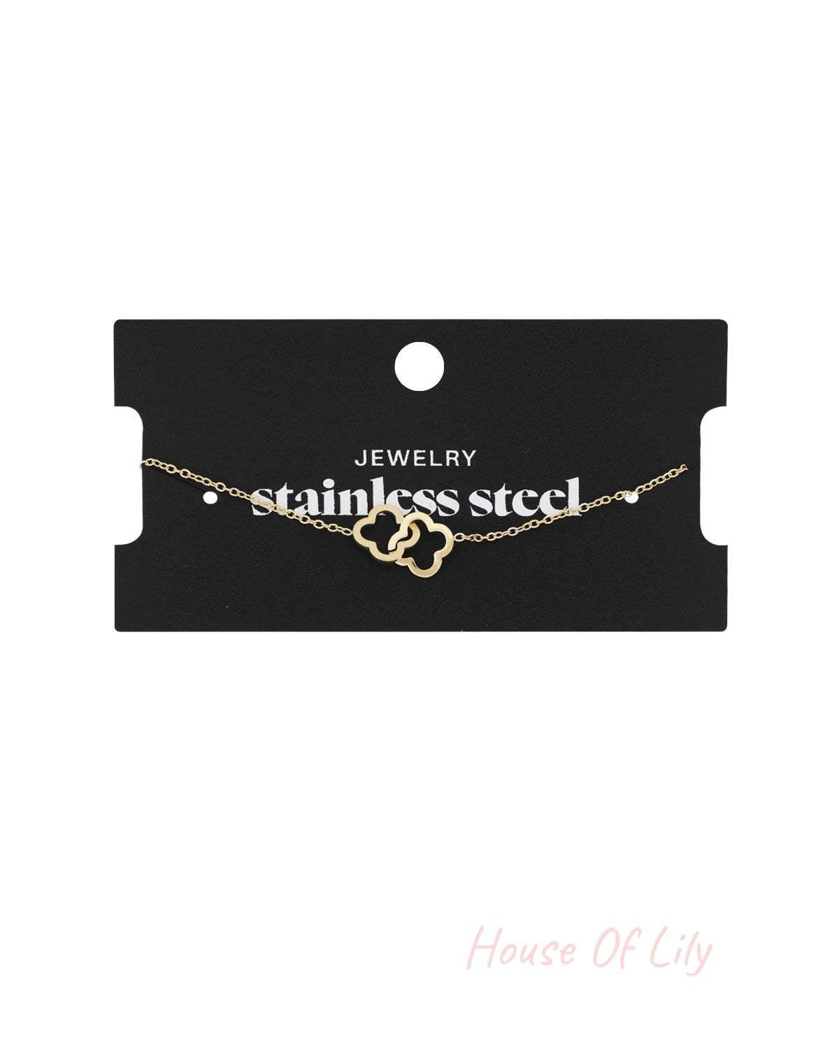 Gold linked clover bracelet displayed on a black card labelled 'stainless steel jewelry'