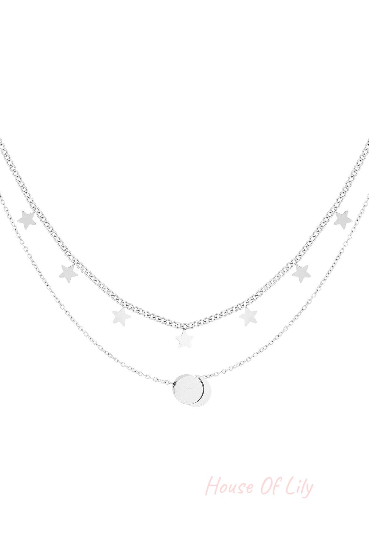 Silver layered necklace with star charms and round pendant on white background