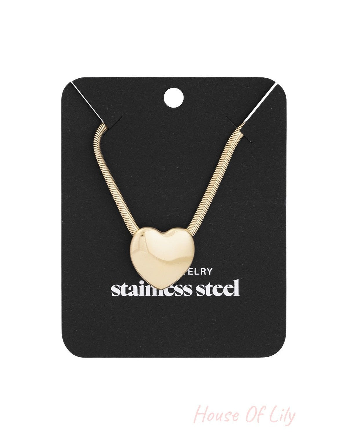 Gold-tone heart pendant necklace displayed on a black card labelled 'stainless steel' showcasing elegant packaging.