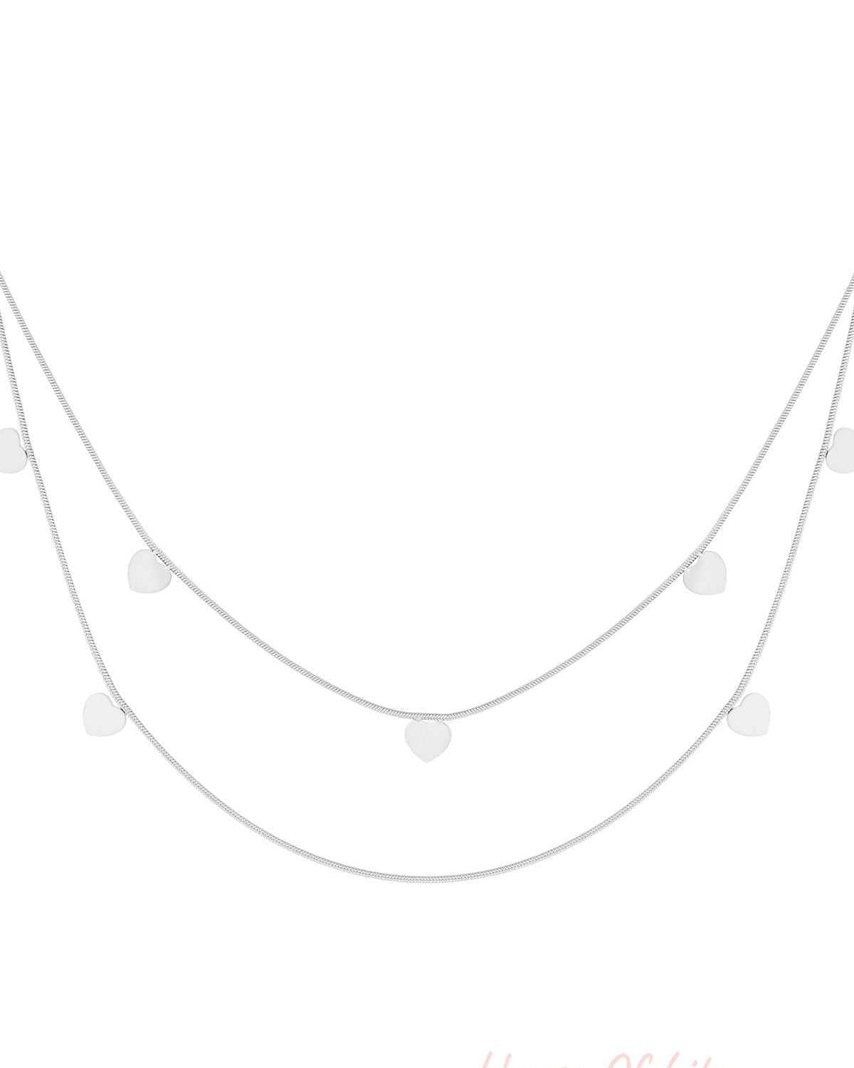 Silver layered necklace with double chains and small heart charms on white background