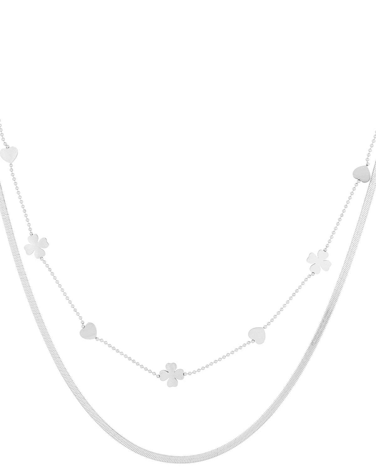 Close-up of silver double-layered necklace with heart and four-leaf clover charms on white background