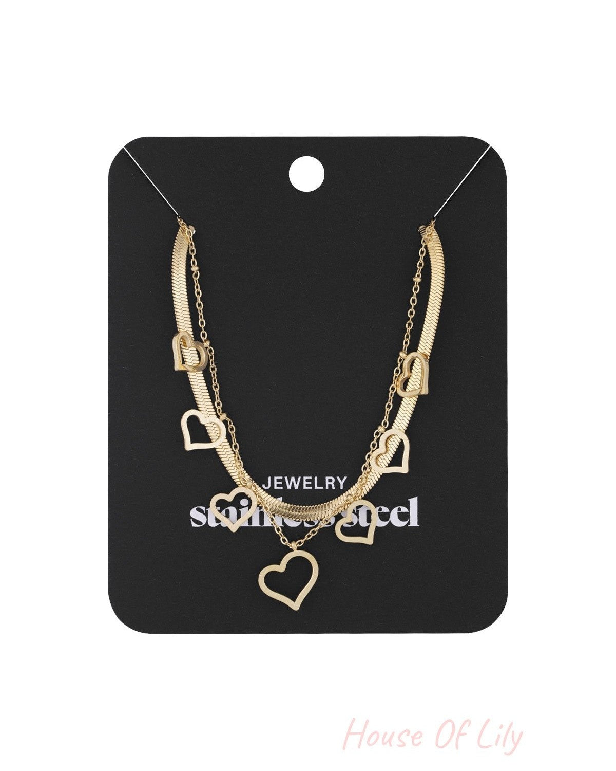 Gold layered necklace with multiple heart charms displayed on a black jewelry card labeled stainless steel