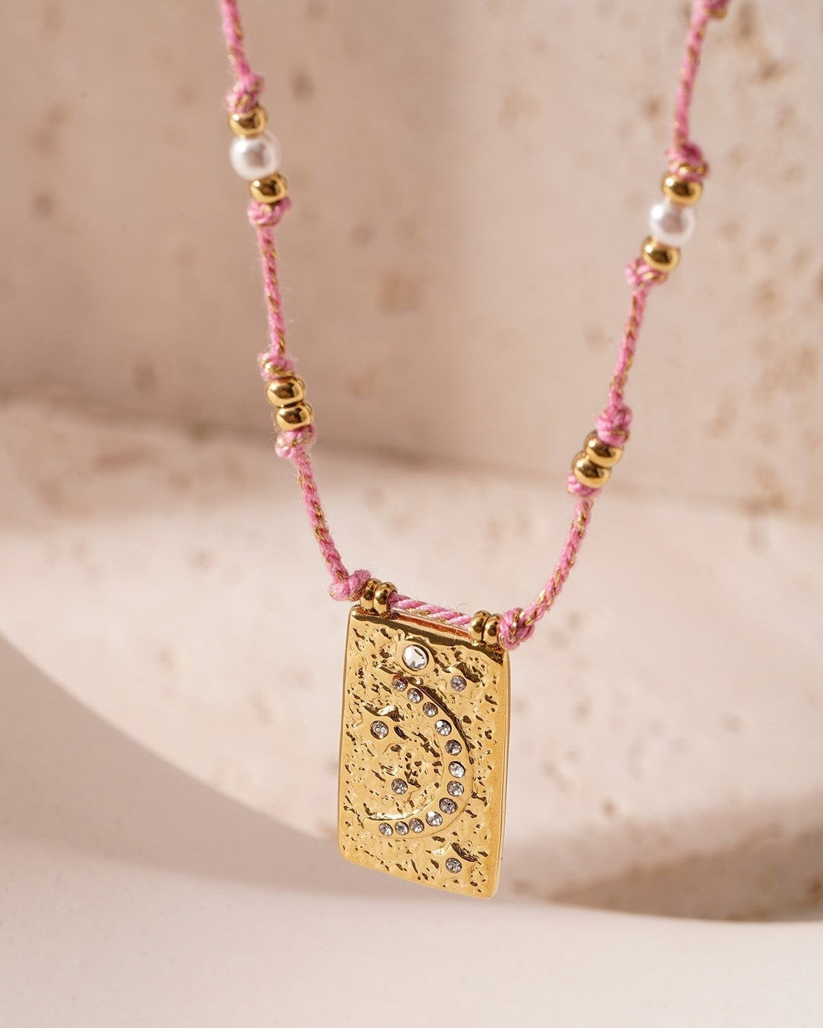 Close-up of orange braided moon pendant necklace with crystal moon pendant on white background