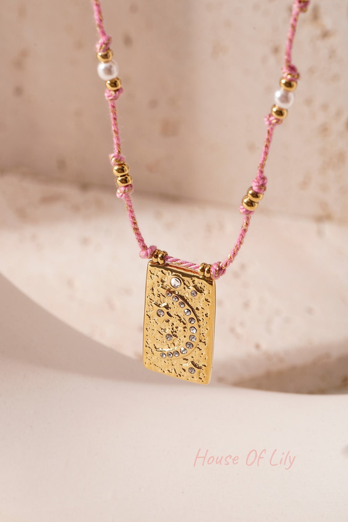 Close-up of orange braided moon pendant necklace with crystal moon pendant on white background