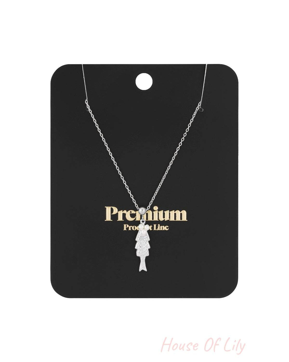Gold fish pendant necklace with pearl accents displayed on white background
