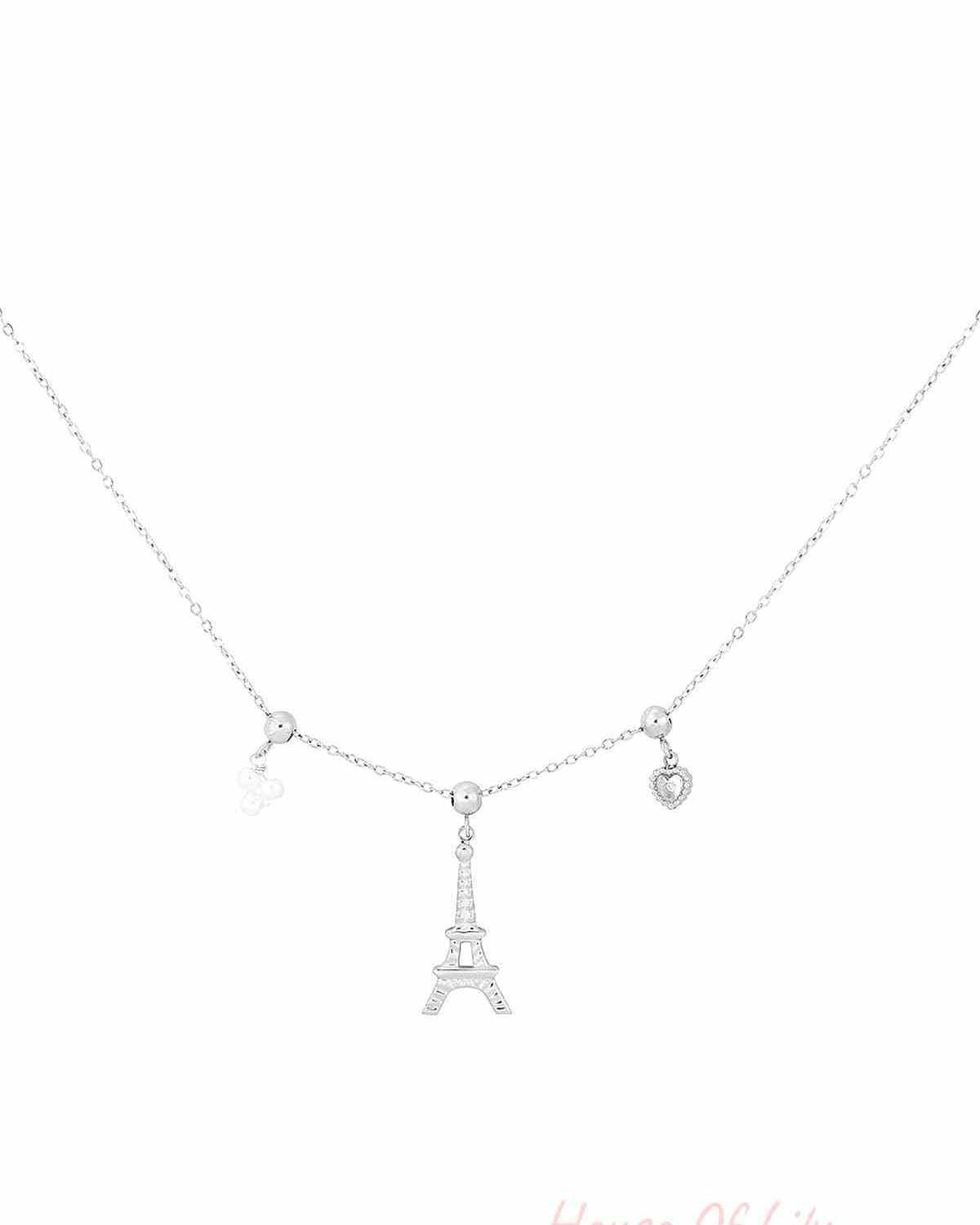 Silver-tone charm necklace featuring an Eiffel Tower centerpiece flanked by small heart and flower charms on a fine chain.
