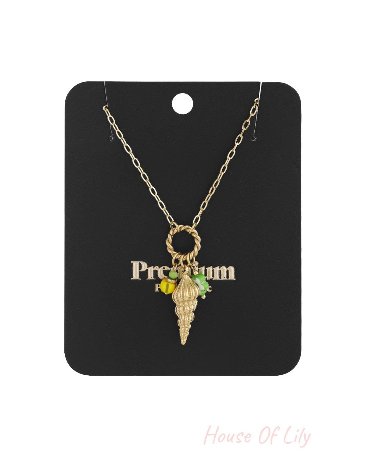 Gold shell charm necklace displayed on black jewellery card with twisted ring clasp