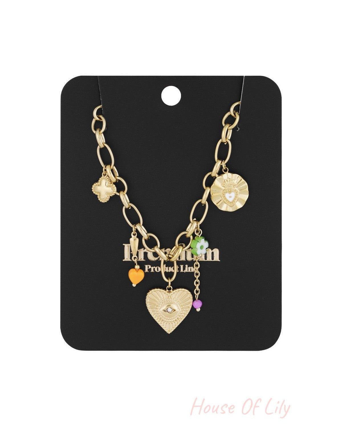 Gold-tone charm necklace displayed on black card packaging, showing detailed charms including a heart with an eye motif and colourful beads