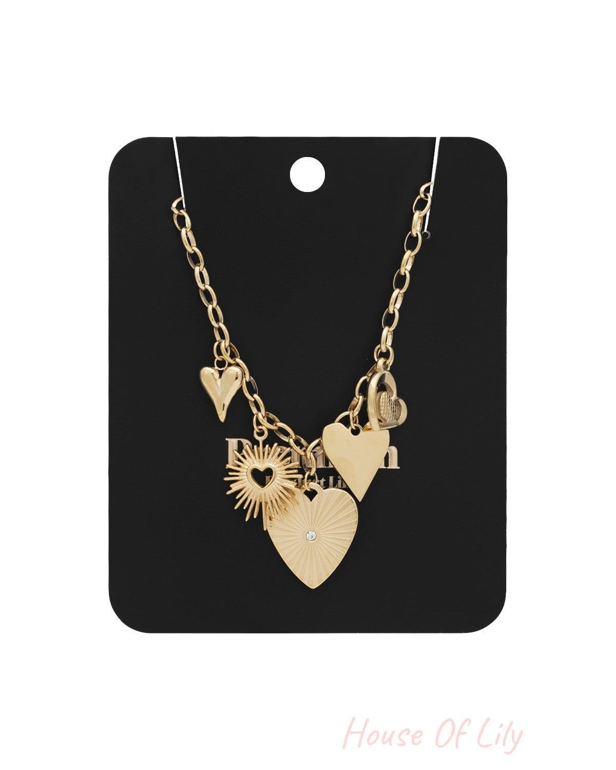 Gold link necklace with heart and sunburst-shaped charms displayed on black card packaging
