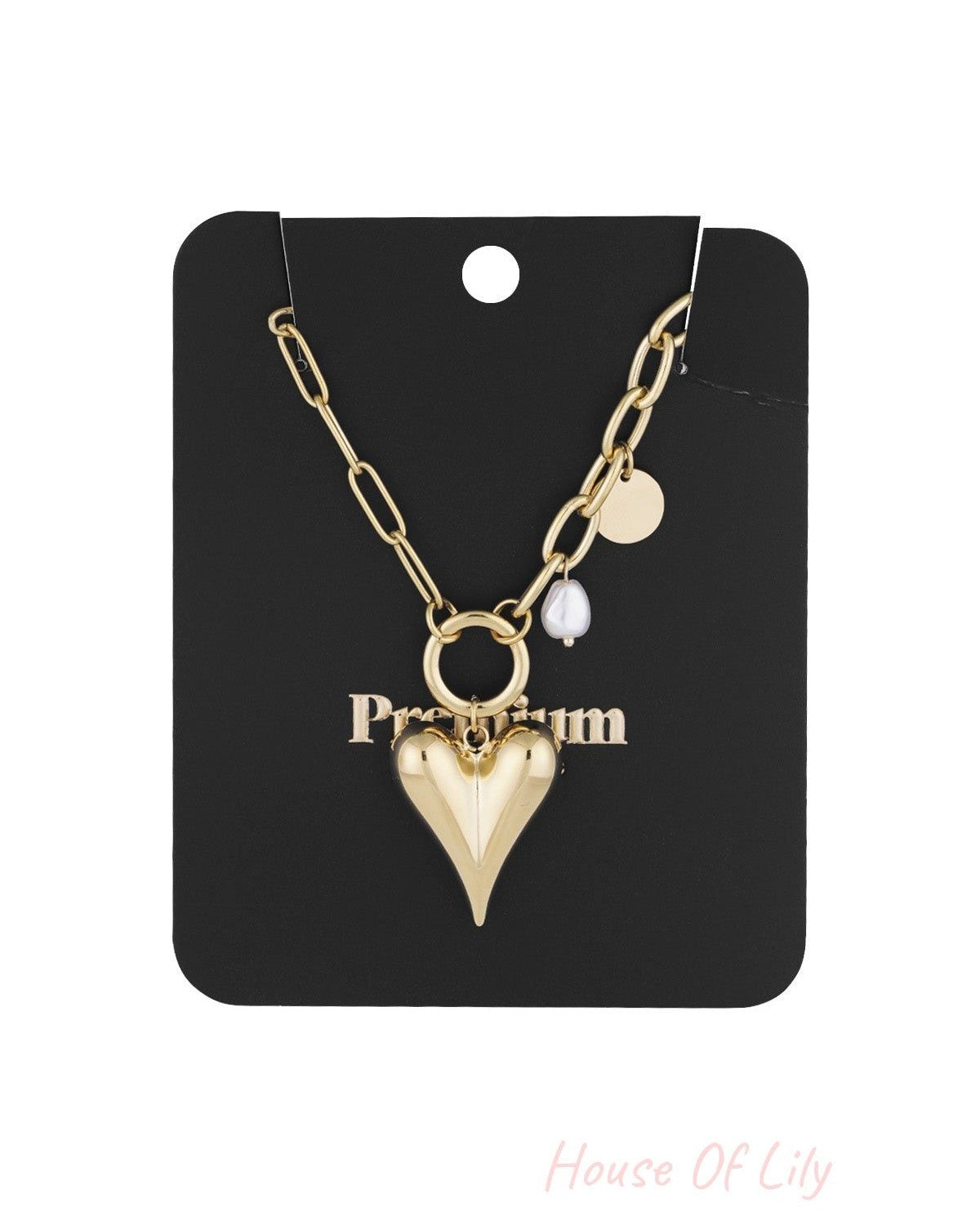 Gold-tone chunky heart pendant necklace with pearl and coin charms displayed on black packaging card