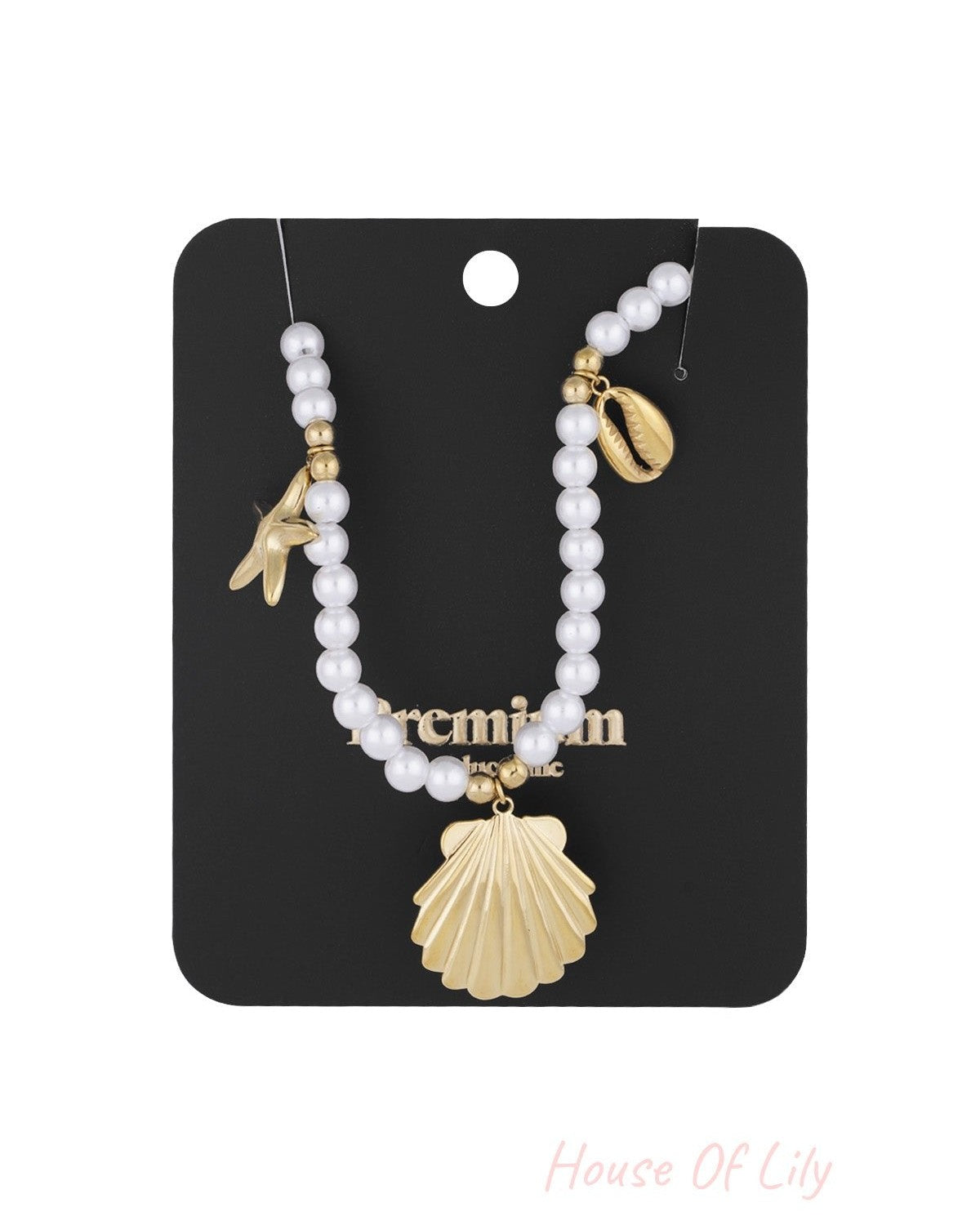 Pearl charm necklace presented on black display card showing detailed sea-inspired gold charms