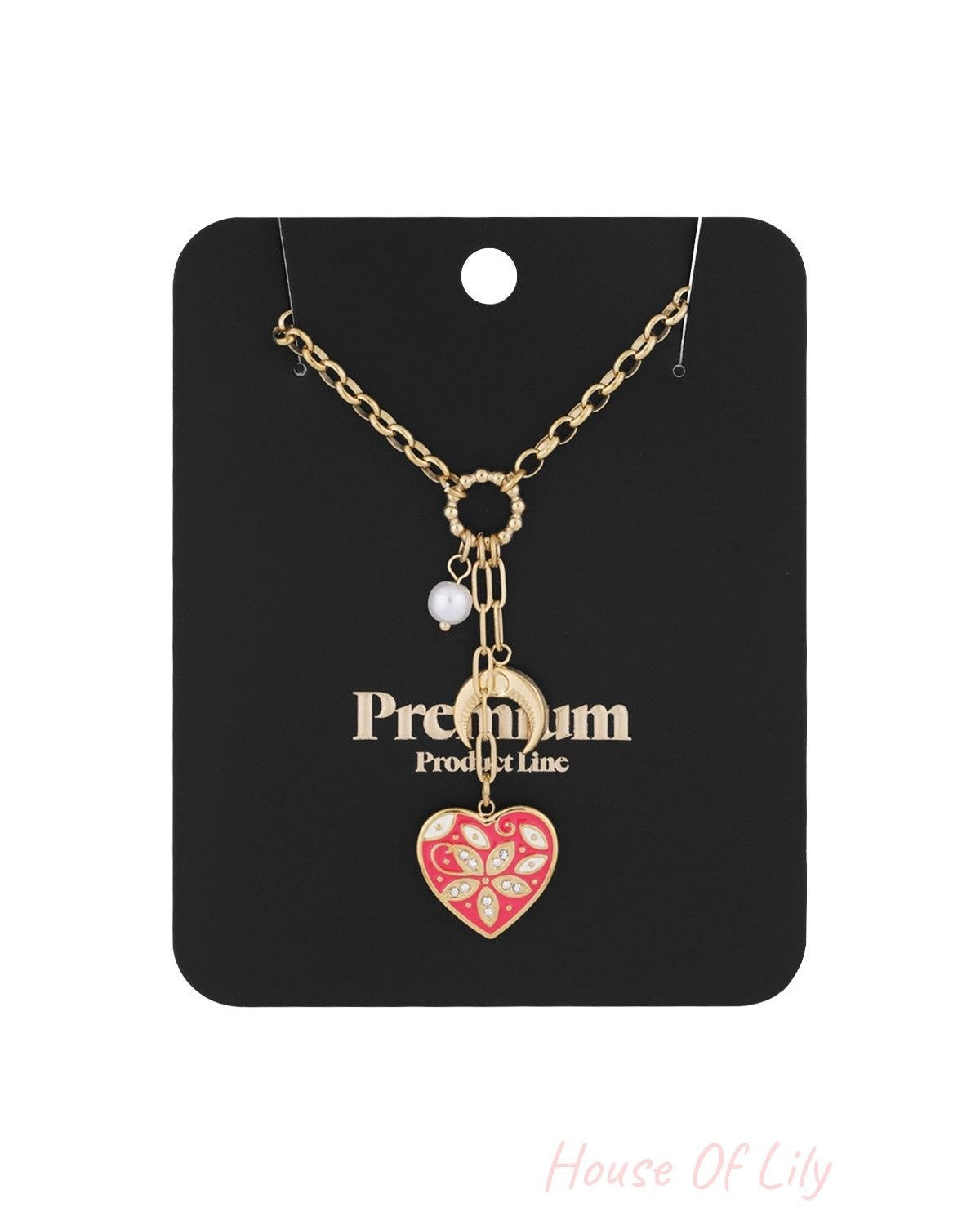 Gold-tone charm necklace displayed on black 'Premium Product Line' card showing red heart, crescent moon, and pearl charms