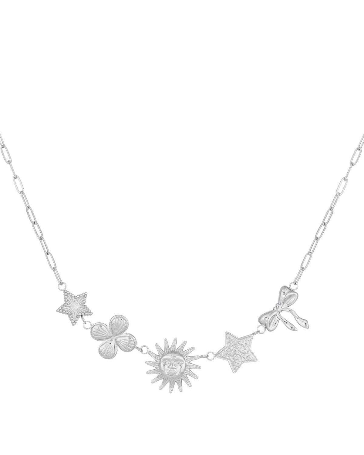 Silver-tone celestial charm necklace with star, clover, sun, textured star, and bow charms laid flat on white background