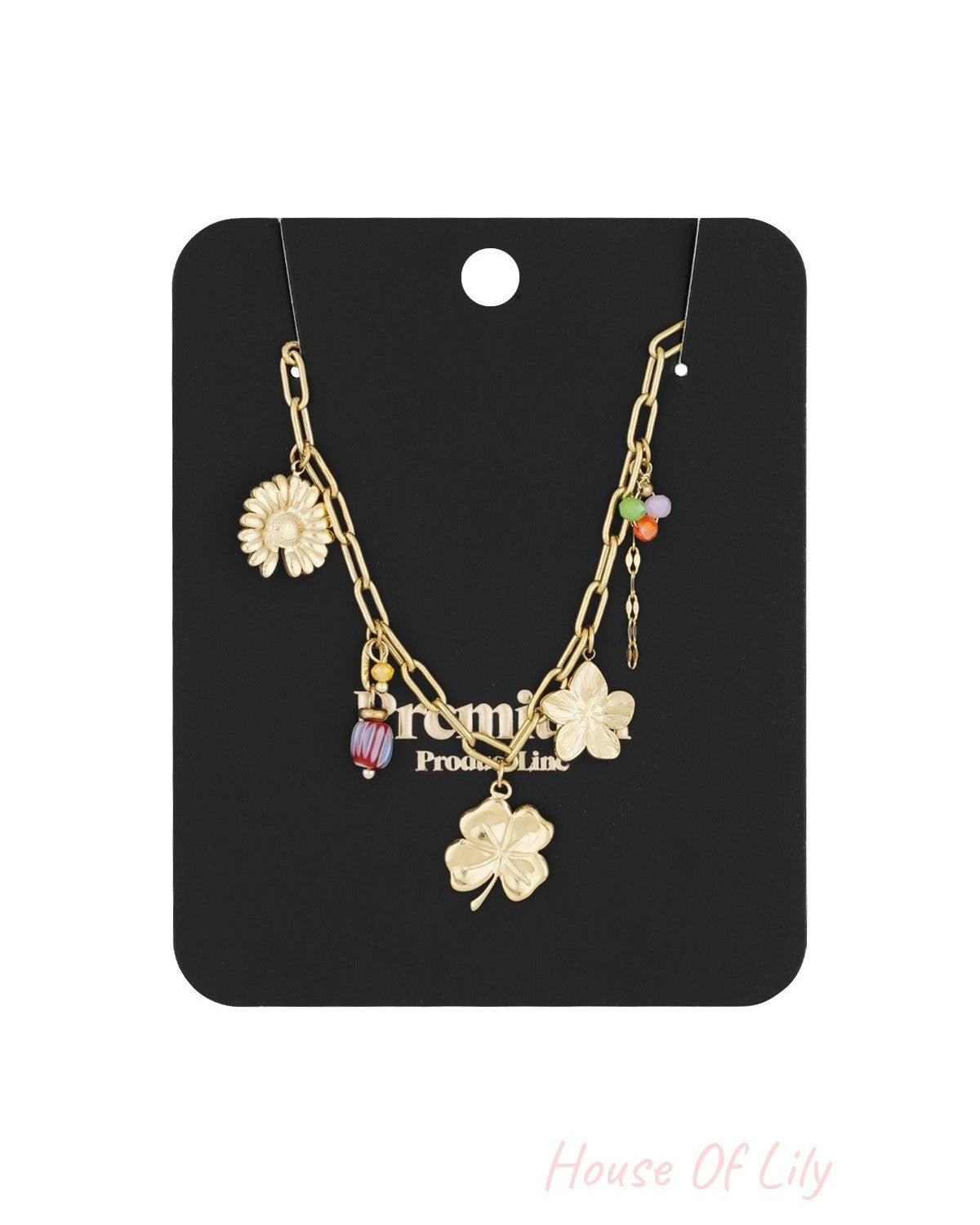 Gold charm necklace packaged on a black card showcasing the mix of flower and bead pendants